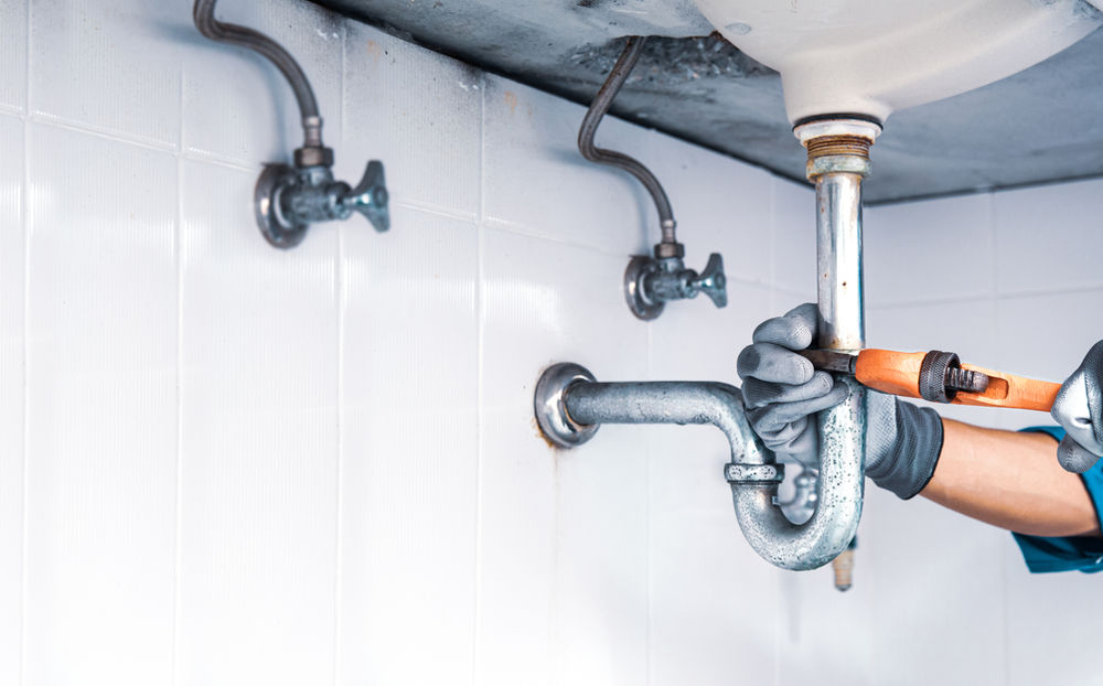 Technician plumber using wrench repair water pipe sink