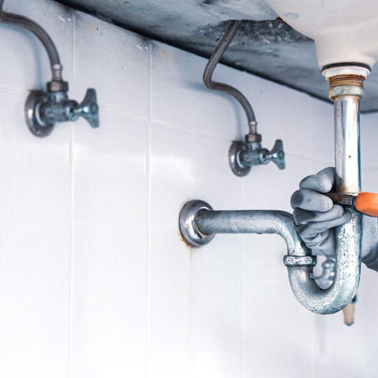 Technician plumber using wrench repair water pipe sink